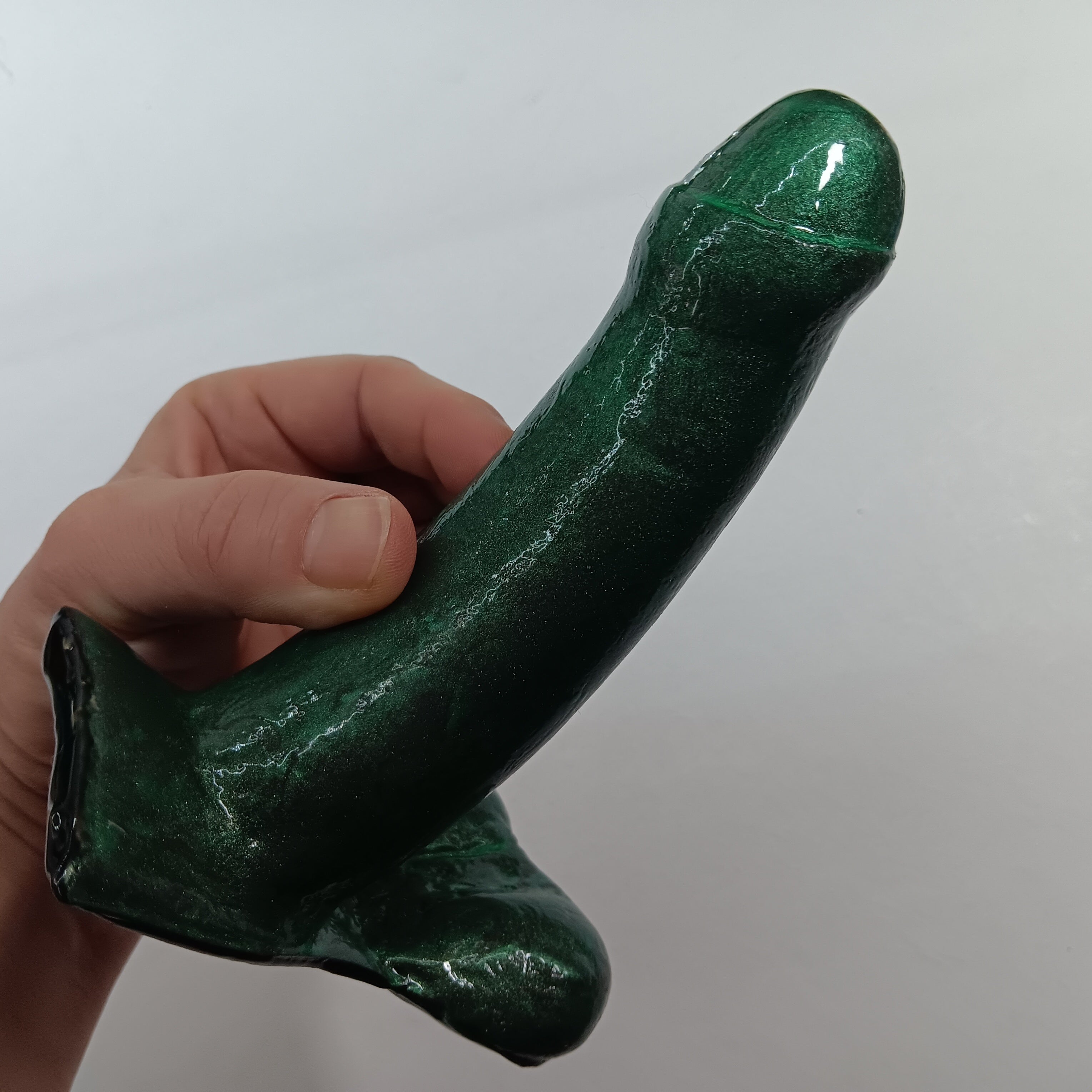 Hand holding the 5 inch uncut SQUEEZE in dark green shimmer color
